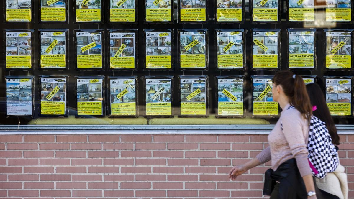 Dos mujeres pasan ante una inmobiliaria con la mayoría de los pisos alquilados o vendidos.