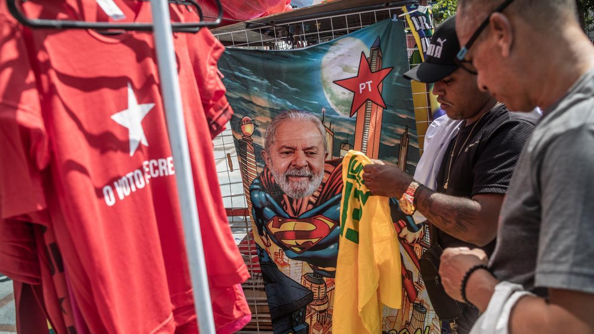 Un hombre compra en un puesto ambulante una camiseta de Lula da Silva.