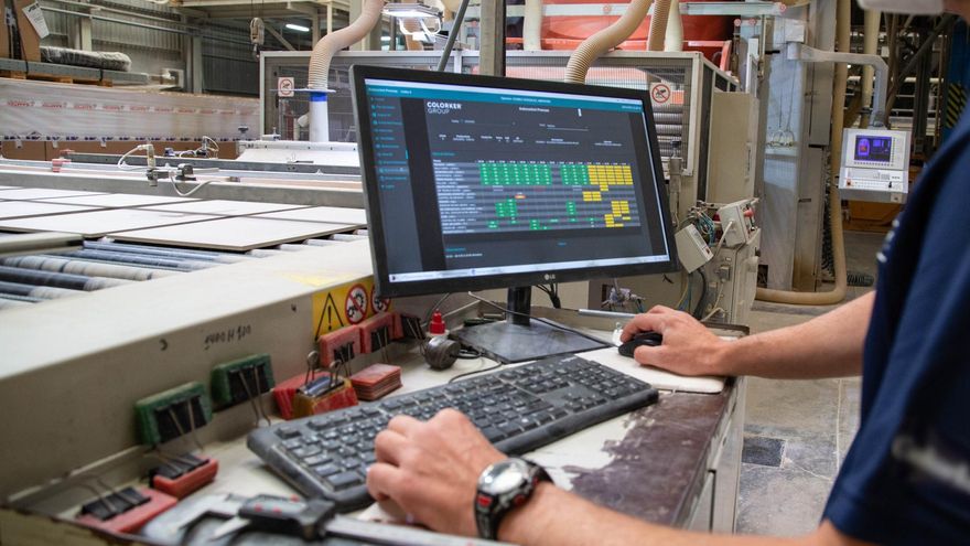 Un operario trabaja con un sistema informático en una fábrica cerámica.