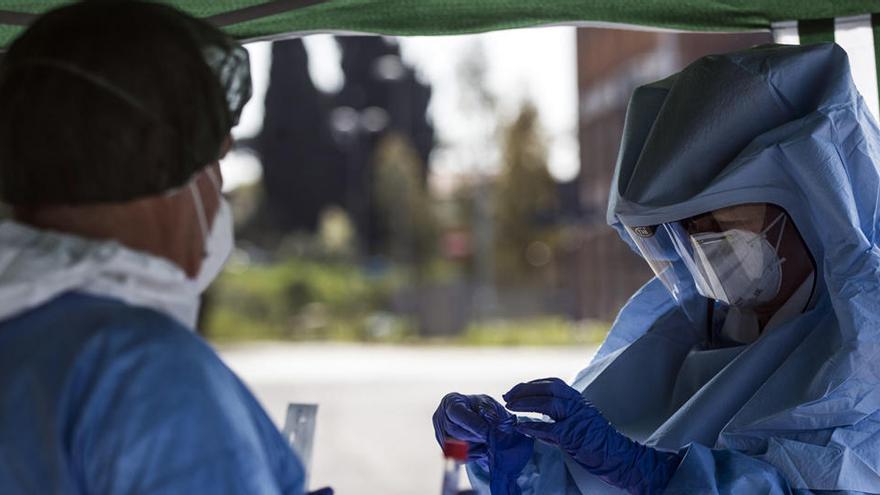 Trabajadores de la salud recogen hisopos y realizan pruebas a los automovilistas para detectar el coronavirus.