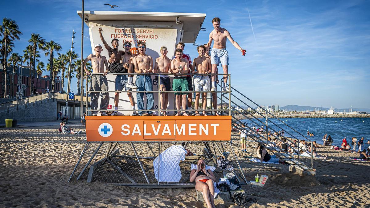 Jóvenes extranjeros subidos a una torre de socorrismo cerrada en la playa de la Barceloneta