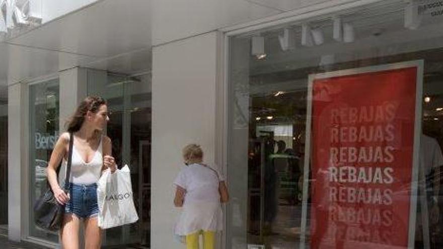 Una joven observa un cartel que anuncia las rebajas en un escaparate de Ibiza.