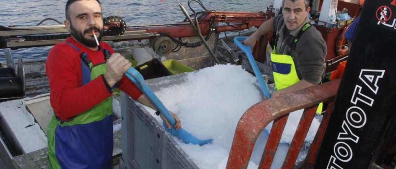 Agustín Vidal y Rafael Villar, tripulantes del &quot;Cristo da Laxe&quot;, cargan hielo en el puerto de Bueu. // Santos Álvarez