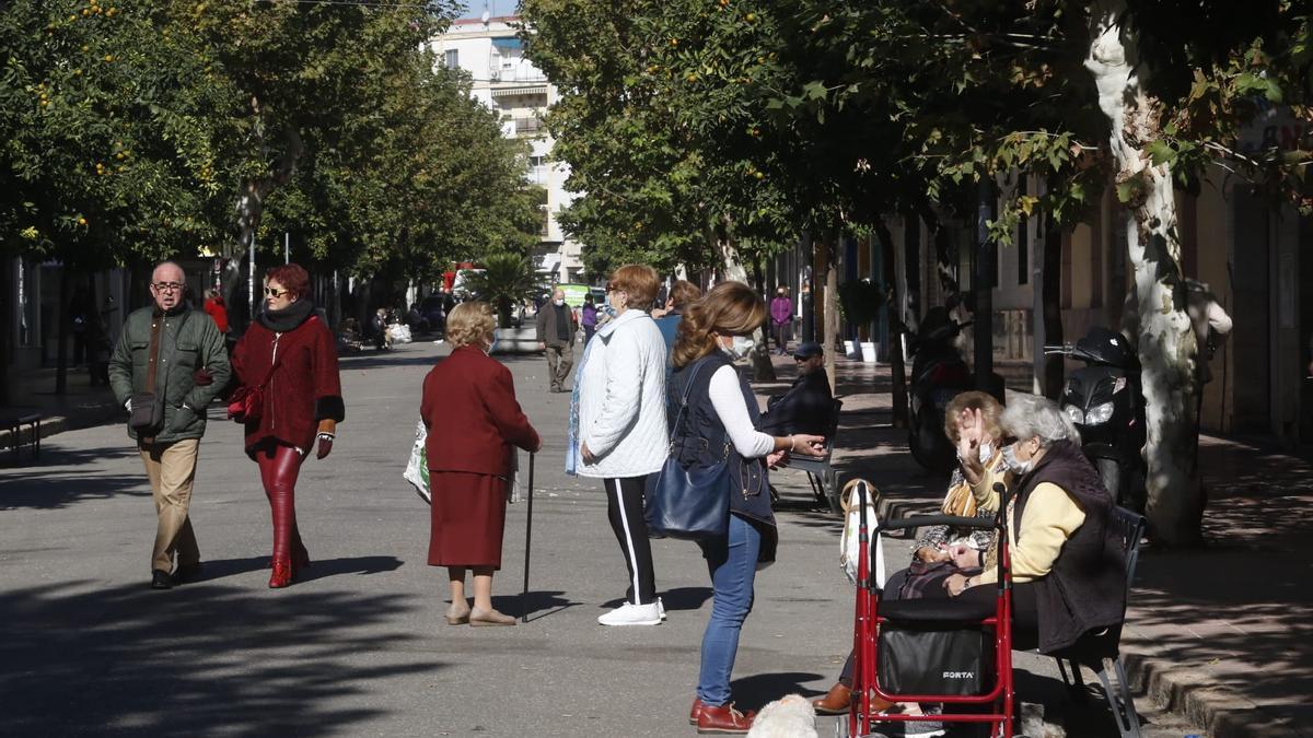 Personas mayores pasean o se sientan en los bancos colocados tras la peatonalización.