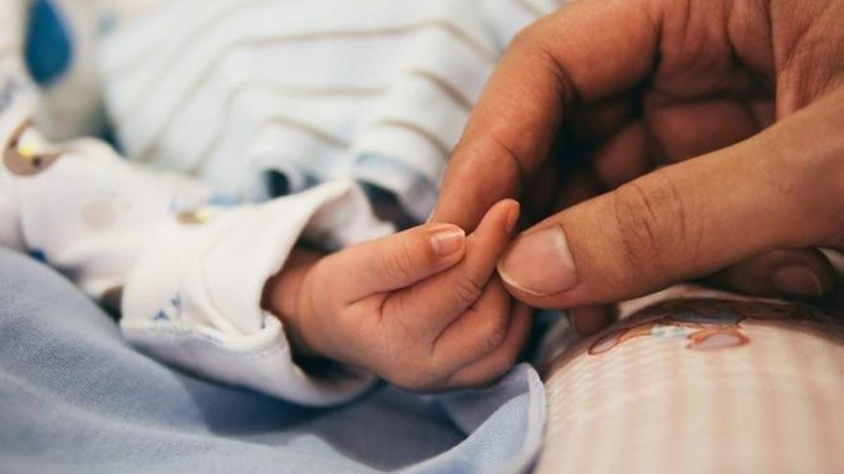 Una madre coge la mano de su hijo recién nacido-