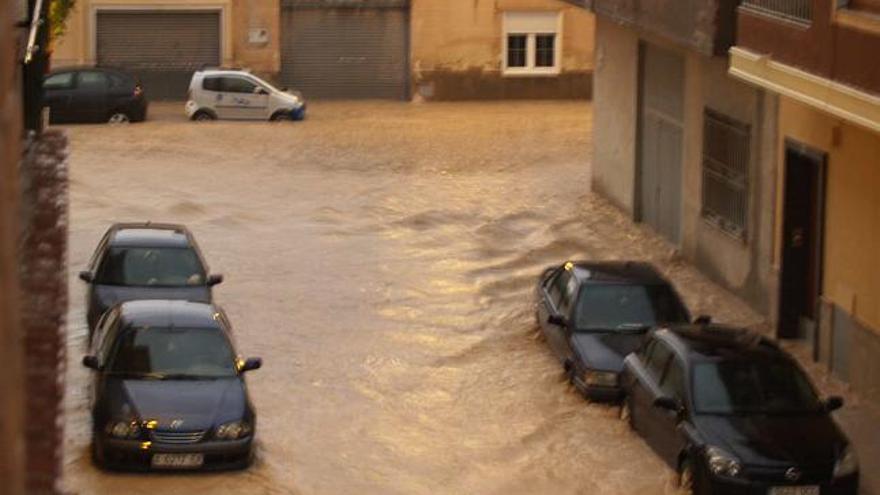 Imagen de una calle en la localidad de Monforte, donde se aprecian numerosos coches cubiertos de agua después de la tromba