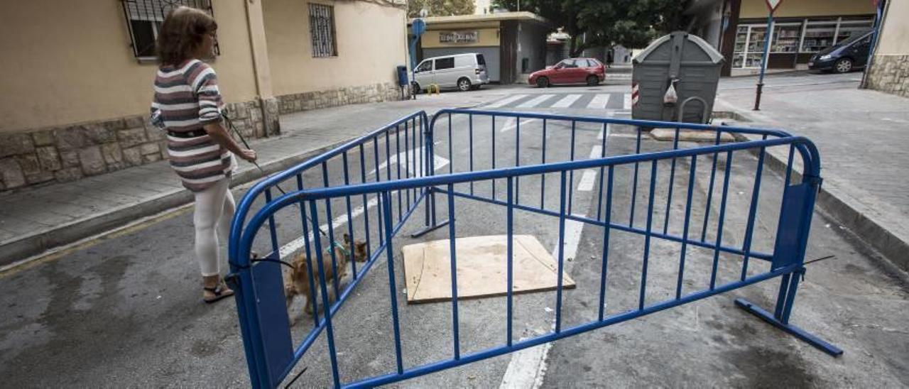 Agujero que lleva un año en la calzada de la calle Moncada, que los vecinos tapan con maderas.