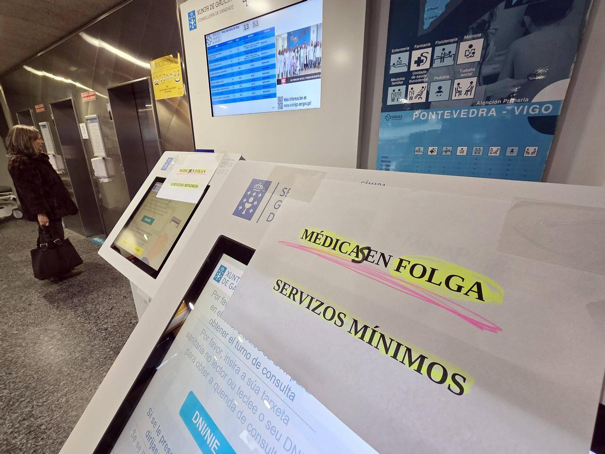 Carteles informativos sobre servicios mínimos en máquinas de citas de un centro de salud.