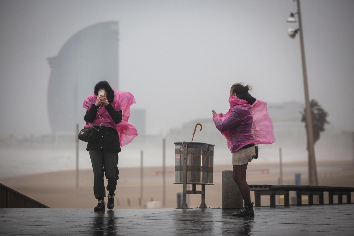 Dos mujeres en el paseo marítimo de Barcelona durante una fuerte borrasca. Foto archivo