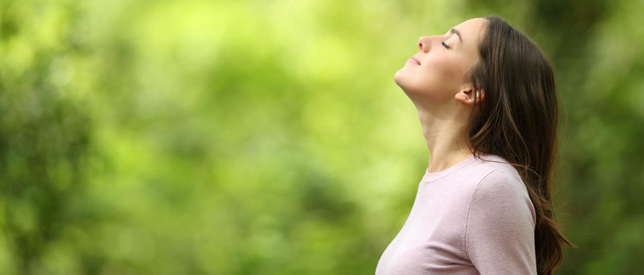 Una chica respira profundamente en un paisaje natural.