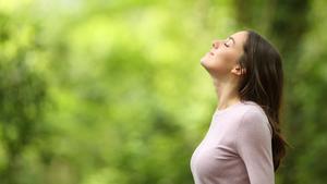 Una chica respira profundamente en un paisaje natural.