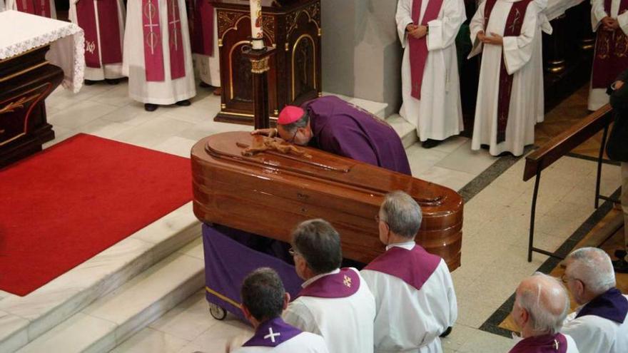 El arzobispo de Oviedo, Jesús Sanz, besa el féretro de Faustino Martínez durante el funeral.