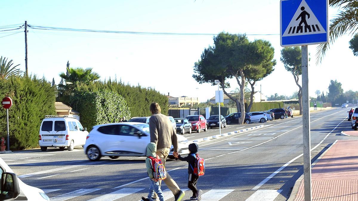 Una familia cruza por el paso de peatones en el peligroso tramo frente al colegio Els Garrofers.