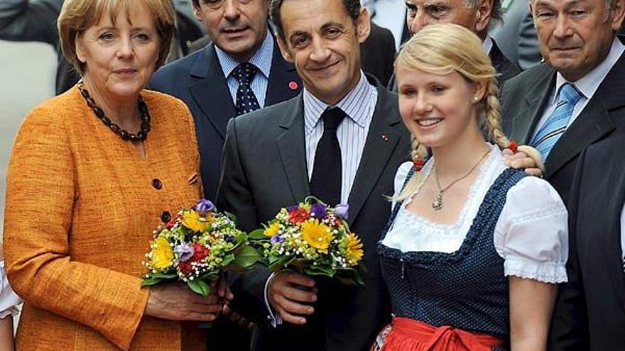 Angela Merkel y Nicolás Sarkozy, con sendos ramos de flores que les entregó una joven bávara. /