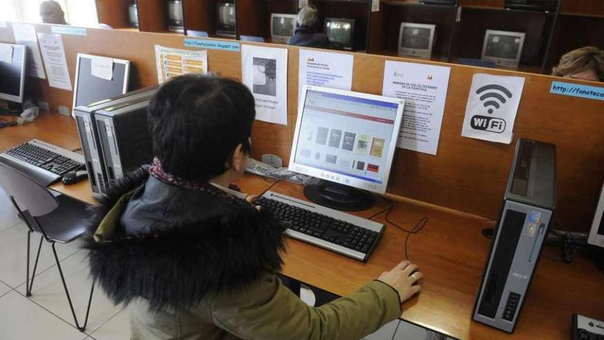 Una usuaria de la Biblioteca Provincial consulta un catálogo de libros digitales ante un ordenador.