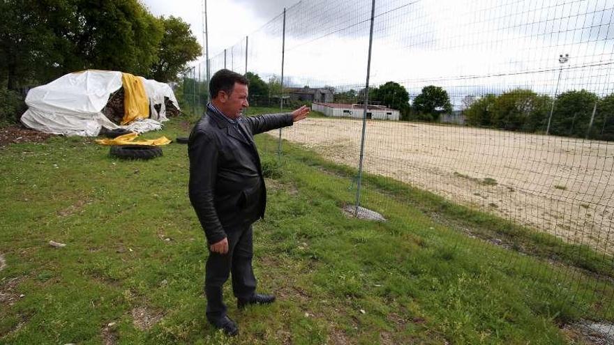 José Vence señala el campo de fútbol, sin césped, con los vestuarios al fondo.  // Bernabé/Gutier