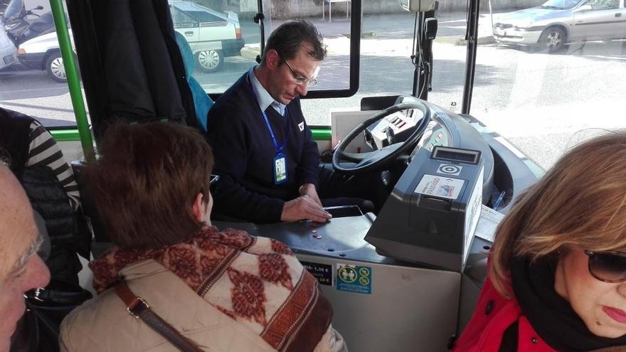 Un conductor de Vitrasa cuenta los céntimos de unos usuarios, esta tarde, en una parada de Chapela. / A.P.