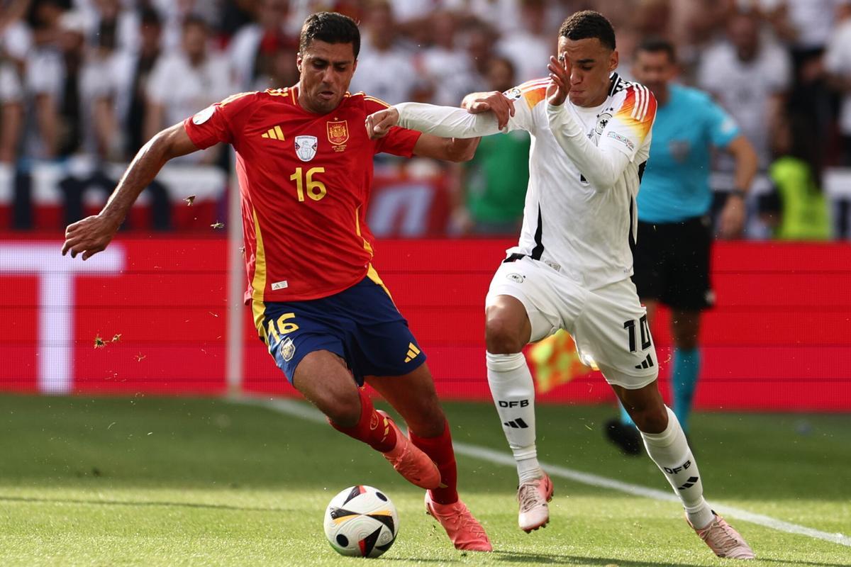 Stuttgart (Germany), 05/07/2024.- Jamal Musiala of Germany (R) in action against Rodri of Spain during the UEFA EURO 2024 quarter-finals soccer match between Spain and Germany, in Stuttgart, Germany, 05 July 2024. (Alemania, España) EFE/EPA/ANNA SZILAGYI. seleccion españa . seleccion alemania. eurocopa 2024 alemania . seleccion españa . seleccion alemania. cuartos. mhparena