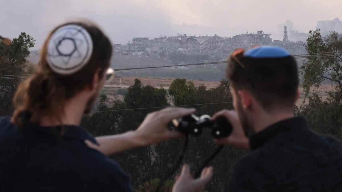 Dos judíos ultraortodoxos observan una zona de Gaza bombardeada desde el sur de Israel.