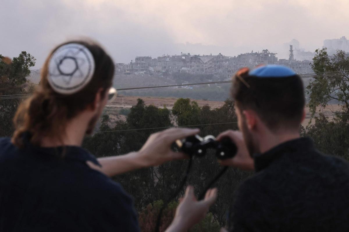 Dos judíos ultraortodoxos observan una zona de Gaza bombardeada desde el sur de Israel.