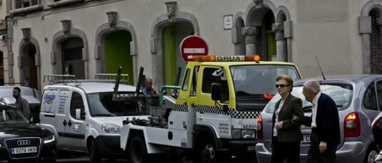 Una grúa municipal estacionada en una calle del centro de la ciudad de Elche, una zona en la que es habitual encontrar vehículos mal aparcados.