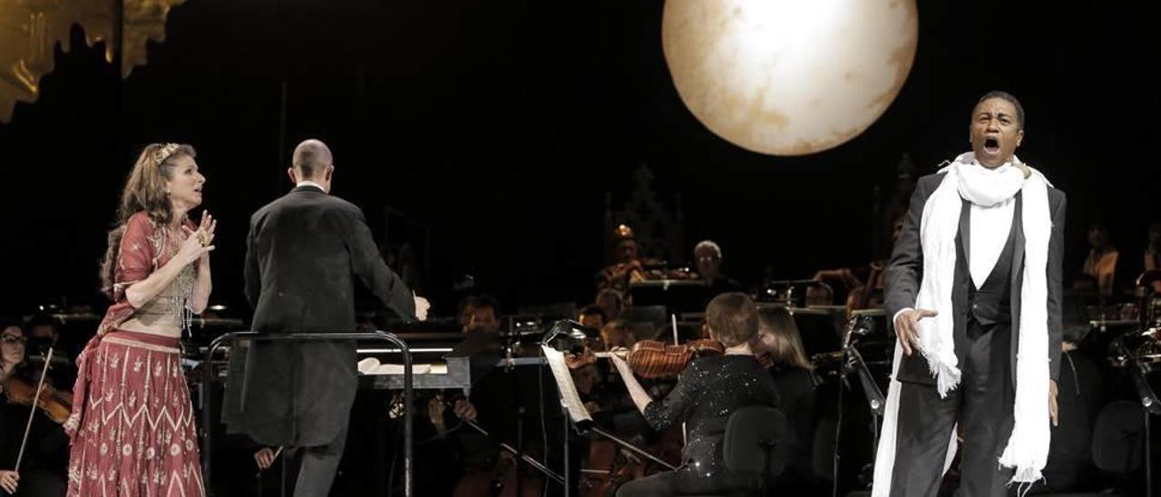 Nicola Beller-Carbone (Salomé) y Mark S. Doss (Jokanaan) cantando bajo la luna y con la orquesta al fondo.