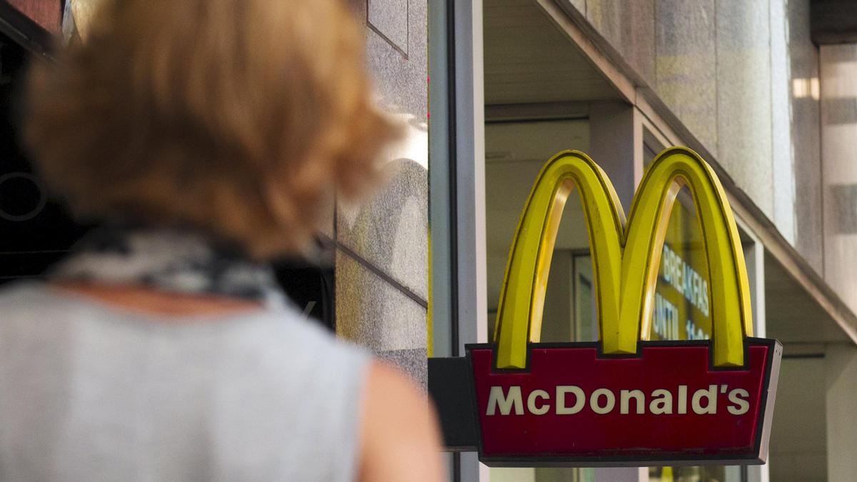 Imagen de archivo de una mujer caminando hacia un McDonald&#039;s.