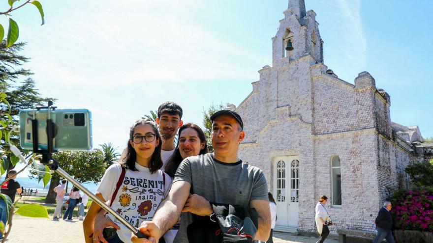 Una familia se hace un selfie frente a la capilla de As Conchas en A Toxa.  | // I. ABELLA