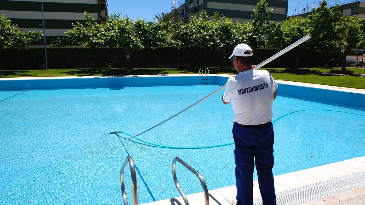 Un hombre limpia una piscina en Córdoba al inicio del verano.