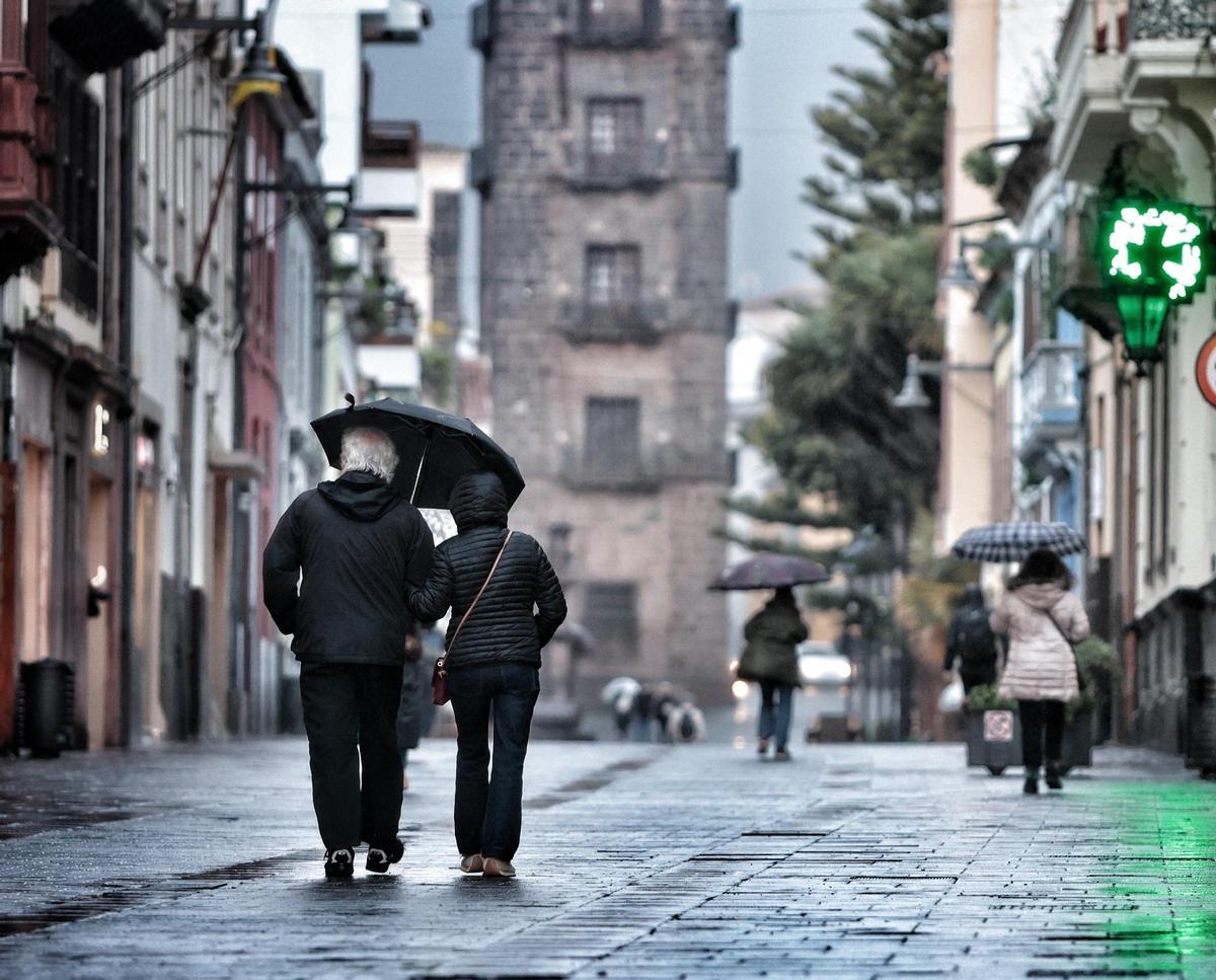 Dos personas paseando por La Laguna mientras llueve