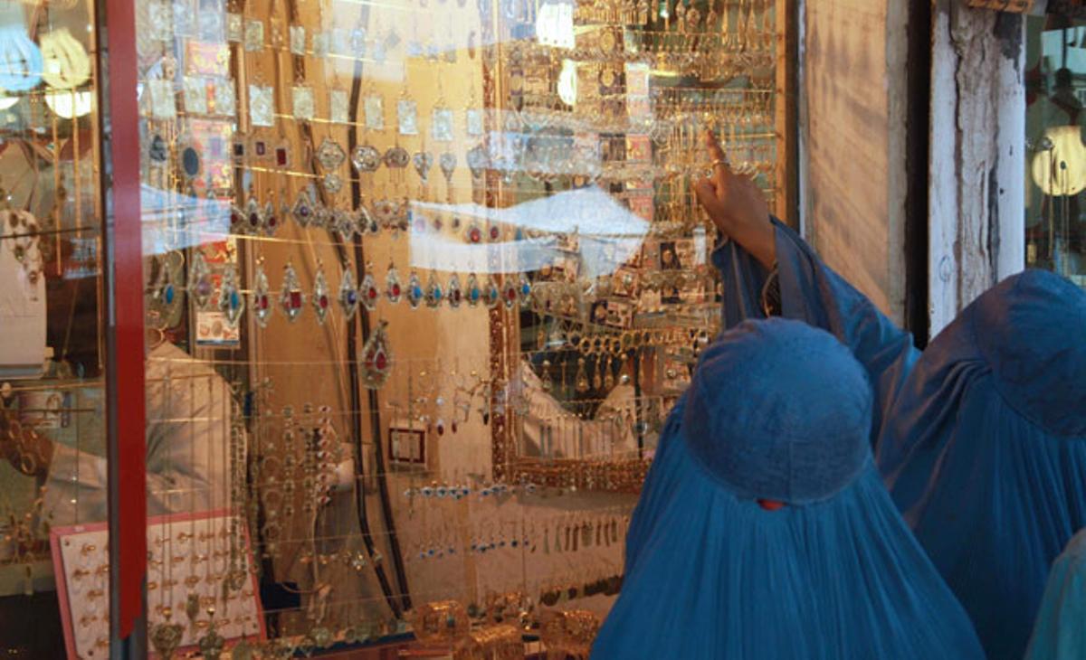 Dues dones amb burca miren l’aparador d’una joieria a Herat, Afganistan.
