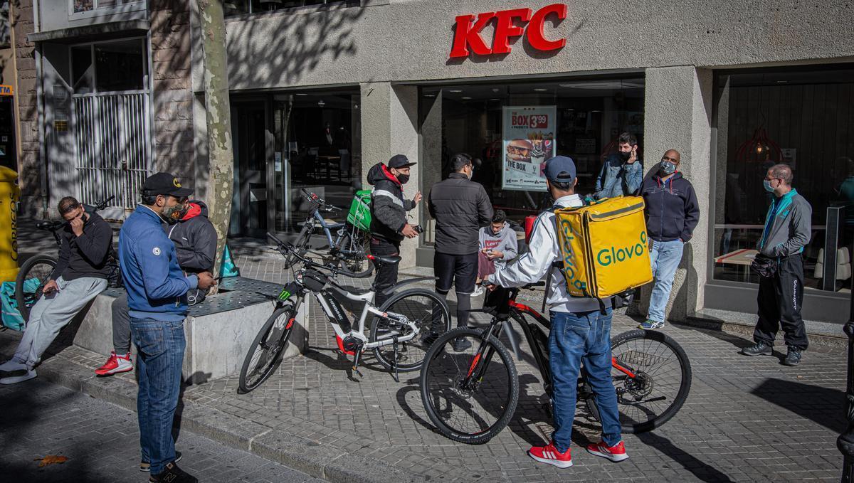 Repartidores de distintas apps de comida a domicilio esperando a la puerta de un restaurante.