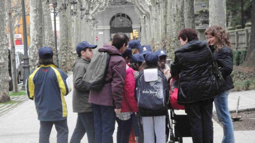 Els escolars, amb gorra de policia, s&#039;acosten a dues vianants que passegen un nadó.