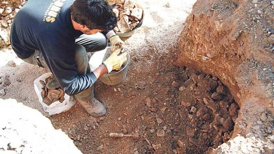 Uno de los arqueólogos va desenterrando restos en un lugar en el que se aprecia la forma circular del viejo pozo.