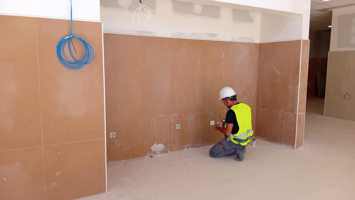 Un obrero coloca unos apliques en la pared