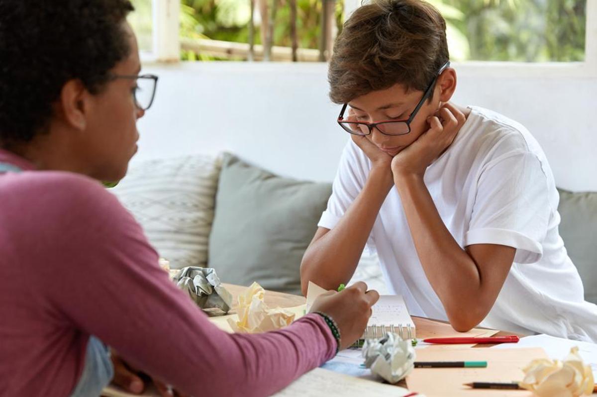 Una auxiliar atiende a uno de sus estudiantes en un aula.