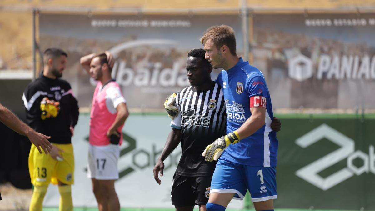 Javi Montoya, portero del Mérida, junto a Koroma, del Linense.