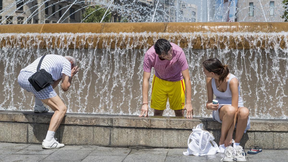 Tres ciudadanos se refrescan en una fuente, el pasado 7 de julio en Barcelona.