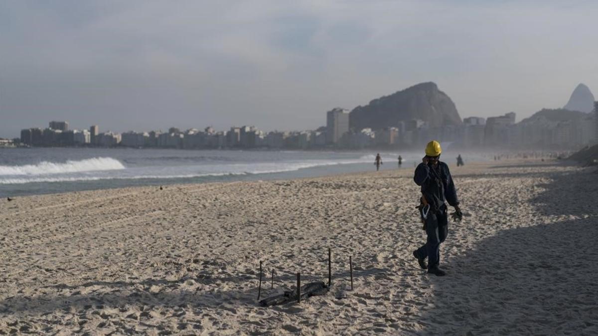 Un obrero de los Juegos Olímpicos observa los restos de un cuerpo humano mutilado en la playa de Copacabana