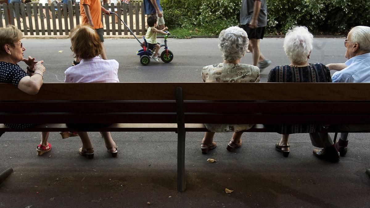 Un grupo de ancianos descansan en un banco en un parque de Barcelona.