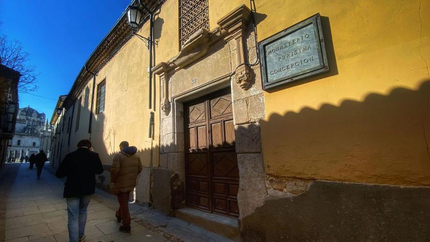 Varias personas transitan por la rúa de los Notarios ante la fachada principal del antiguo monasterio. | Alba Prieto
