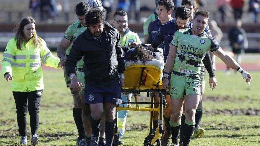 Jugadores de ambos equipos retiran a Brizuela en camilla. // R.Grobas