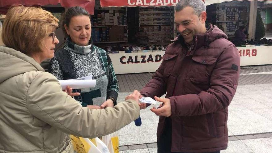 Dos participantes en la campaña de concienciación entregan la pegatina a un vecino.