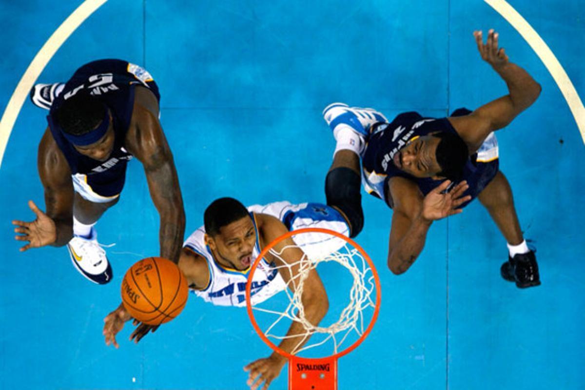 El jugador del New Orleans Hornets Eric Gordon encistella mentre dos defenses dels Memphis Grizzlies intenten evitar el punt, a la pretemporada de la Lliga NBA a Nova Orleans (Estats Units).