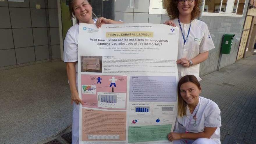 María Covadonga Fernández, María Gómez y Marta Fuertes, con el póster de su estudio a la entrada del local de fisioterapia de Cangas.