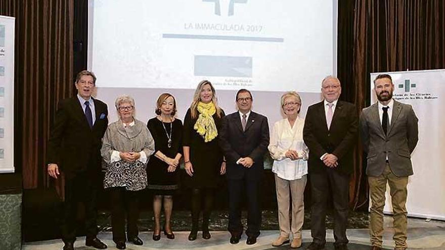 Foto de familia de las autoridades asistentes con los colegiados galardonados con la insignia de oro.