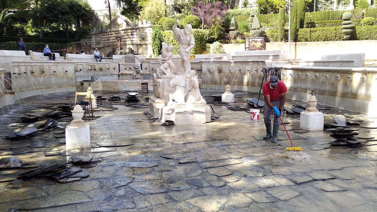 Un operario trabaja en el acondicionamiento del fondo del estanque central de la Fuente del Rey.