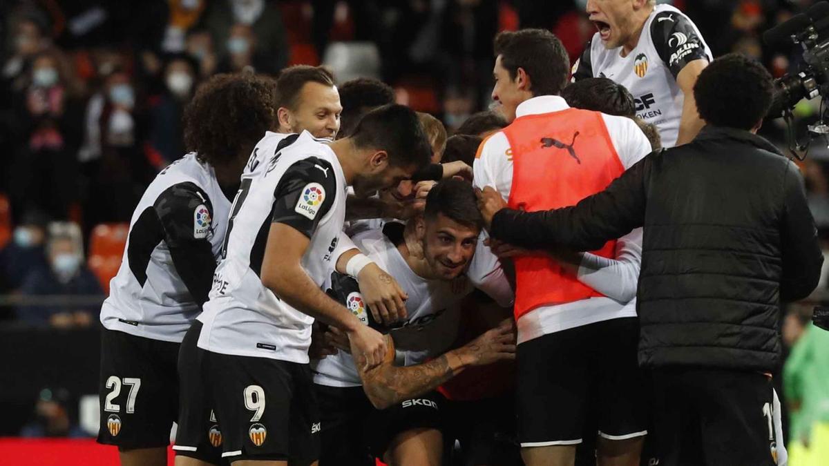 Los futbolistas del Valencia celebran el gol de Piccini, que supuso el 2-1, mientras el italiano trata de salir de la montonera.  | J.M. LÓPEZ