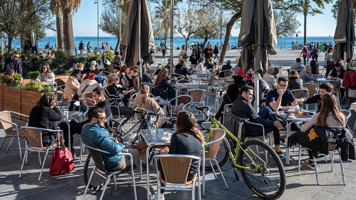 Una concurrida terraza de la Barceloneta, con el mar de fondo.