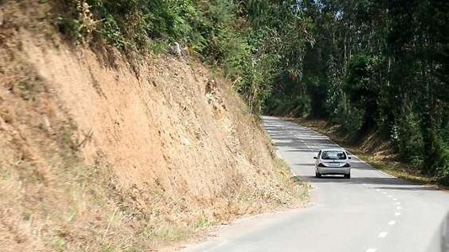 Un coche circula junto a uno de los argayos en la carretera a Macua.